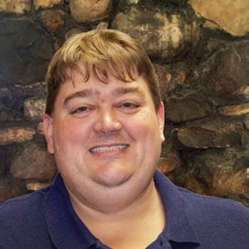 Kris Theilen in front of stone wall.