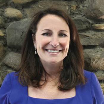 Leslie Sgro in front of stone wall.