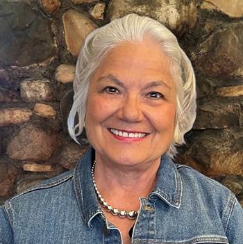 Nancy Eck in front of stone wall.